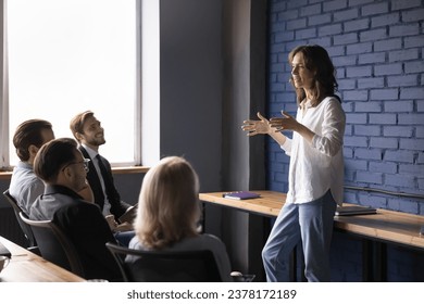 Attractive young company speaker talk to different ages employee on business meeting, help defines task and corporate goal. Teammates group discuss work on project in boardroom. Brainstorm, leadership - Powered by Shutterstock