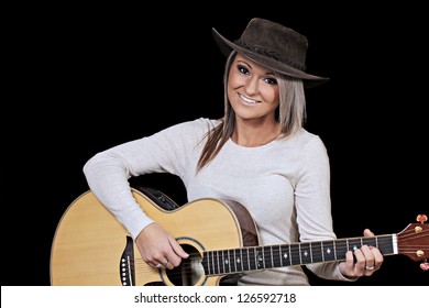 Attractive young country woman playing acoustic guitar