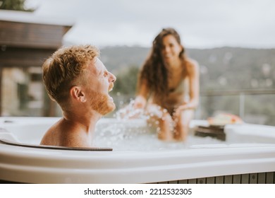 Attractive young couple enjoying in outdoor hot tub on vacation - Shutterstock ID 2212532305