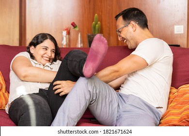 Attractive Young Couple Having A Tickle Fight In The Couch At Home