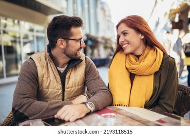 Attractive young couple in love sitting at the cafe table outdoors - Powered by Shutterstock