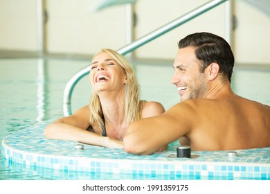 Attractive young couple in love smiling in the indoor swimming pool