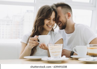 Attractive young couple on a date in a restaurant. Handsome guy is trying to say something in his girlfriend's ears or to kiss her in a cheek. Close up