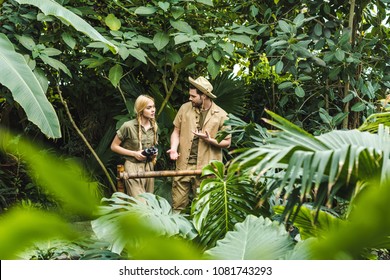 attractive young couple in safari suits holding hands and hiking in jungle
