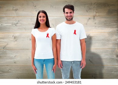 Attractive young couple wearing aids awareness ribbons against bleached wooden planks background