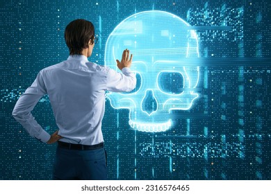 Attractive young european businessman using glowing digital blue glitch skull hologram on dark background. Virus, crime and hacking concept