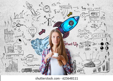 Attractive Young European Woman Drinking Coffee On Concrete Background With Colorful Launching Rocket Sketch. Entrepreneurship Concept