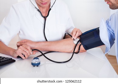 Attractive Young Female Doctor Or Nurse Taking A Male Patients Blood Pressure Using A Sphygmomanometer