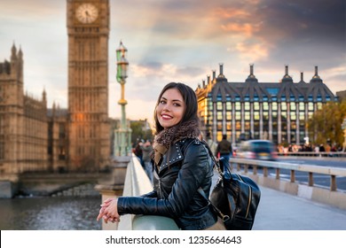 Attractive, young, female London traveler tourist enjoys the view to the Westminster Palace and Big Ben clocktower touring a sightseeing city trip