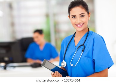attractive young female nurse holding tablet computer at workplace