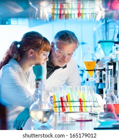 Attractive Young Female Scientist And Her Senior Male Supervisor Looking At Cell Colony Grown In The Petri Dish In Life Science Research Laboratory (biochemistry, Genetics, Forensics, Microbiology..)