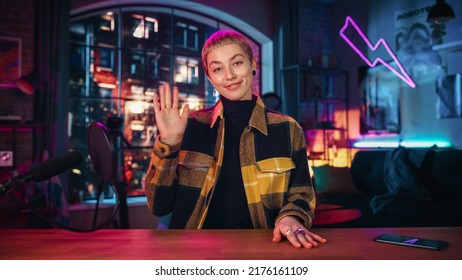 Attractive Young Female Talking Into Microphone While Recording Radio Show from Her Loft Apartment. Happy Woman with Short Hair Talking on Camera and Recording Podcast Live on Social Media. - Powered by Shutterstock