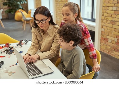 Attractive Young Female Teacher In Glasses Showing Scientific Robotics Video To Children, Using Laptop In Classroom