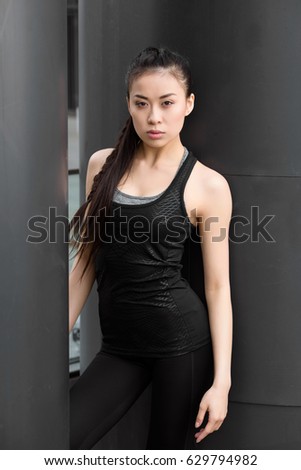 Attractive young fitness woman in sportswear posing and looking at camera