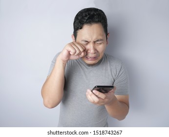 Attractive Young Funny Asian Man Reading Texting Chatting  On His Phone, Bad News, Sad  Crying Expression