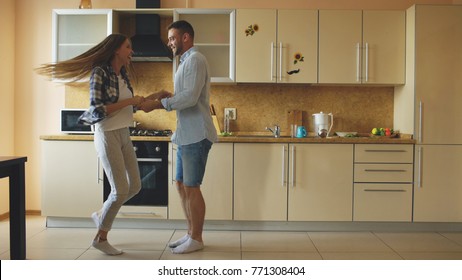 Attractive young funny couple have fun dancing while cooking in the kitchen at home