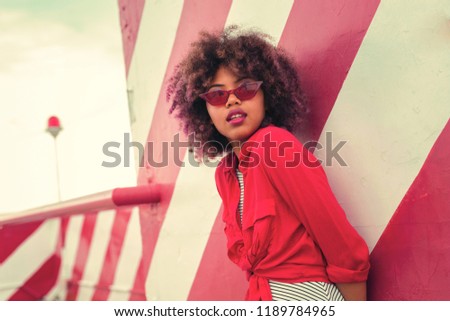 Similar – Young woman with curly hair near a modern colorful building