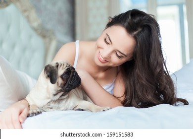 Attractive Young Girl With Dog While Laying On A Bed