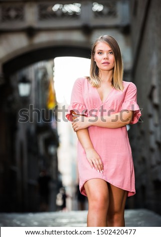 Attractive young girl in pink dress enjoying warm summer day strolling at Barcelona streets