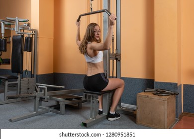 Attractive young girl in sport wear working out with fitness equipment in a professional gym. Training in gym. Sport concept. - Image