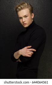Attractive young guy posing in studio, blond hair looking at the camera