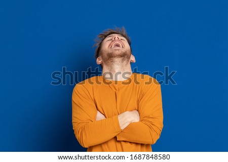 Attractive young guy with a yellow T-shirt on a blue background