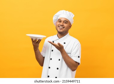 Attractive Young Handsome Asian Man Chef In Uniform Holding Empty Plate Delicious Dish Menu Good Taste On Isolated. Cooking Indian Man Occupation Chef Or Baker People In Kitchen Restaurant And Hotel.