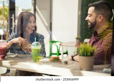 Attractive young Hispanic friends having sandwiches and smoothies for lunch - Powered by Shutterstock