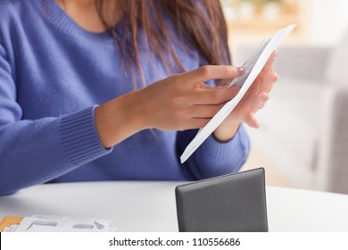 Attractive Young Hispanic Woman Sitting At Table Paying Bills And Doing Banking Wearing Blue Sweater.