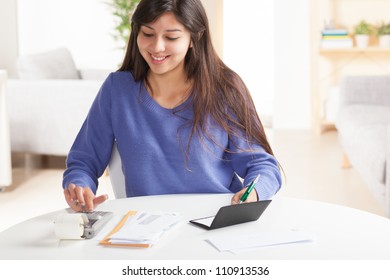 Attractive Young Hispanic Woman Sitting At Table Paying Bills And Doing Banking Wearing Blue Sweater.