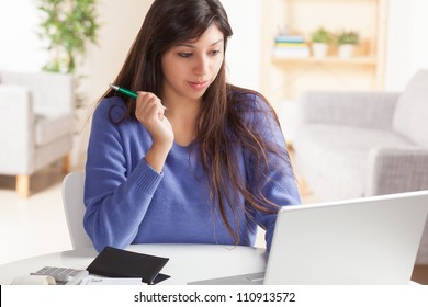 Attractive Young Hispanic Woman Sitting At Table Paying Bills And Doing Banking Wearing Blue Sweater.