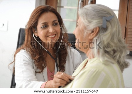 Attractive young Indian doctor sitting with senior patient. Doctor giving consultation to an elderly woman. An elderly patient having a routine checkup from a family doctor. Elderly patient diagnosis. Stock fotó © 