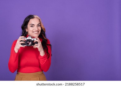 Attractive Young Lady Taking A Photo With Her Film Camera Over A Violet Background.  Copy Space. Studio Shot.