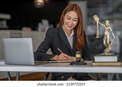 Attractive Young Lawyer In Office Business Woman And Lawyers Discussing Contract Papers With Brass Scale On Wooden Desk In Office. Law, Legal Services, Advice, Justice And Real Estate Concept.