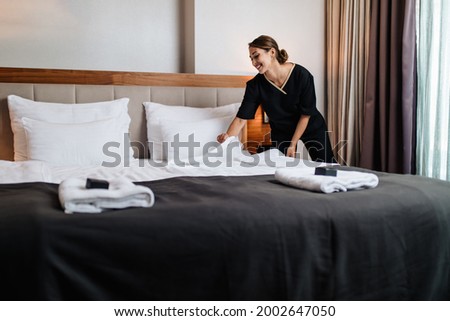 Attractive young maid tidying the hotel room.