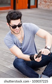 Attractive Young Male Model Playing Games On A Smart-phone