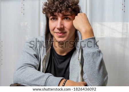 Similar – Portrait of a smiling Caucasian man in his 20s wearing a sweatshirt against a dark background.