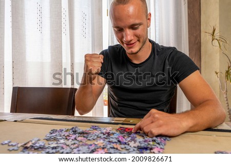 Attractive young man doing a puzzle with his fist raised celebrating that he is able to find his way by mastering his frustration and anxiety. Training concept