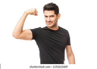 Attractive young man dressed in black tshirt showing his biceps over white background