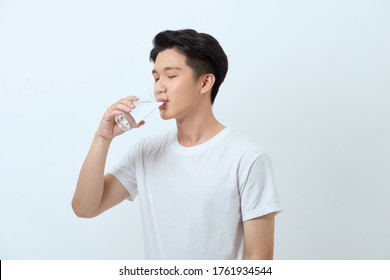 Attractive young man is drinking water from a glass.