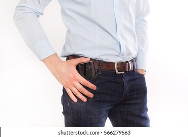 Attractive Young Man In Jeans And Shirt Putting Cell Phone In Front Pocket, Against White Background