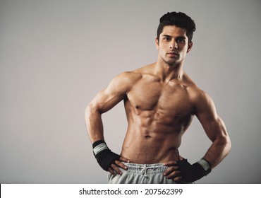 Attractive young man with muscular physique posing on grey background. Hispanic male fitness model standing with his hands on hips. - Powered by Shutterstock