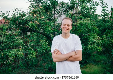 Attractive young man, portrait of a handsome guy, sincerely smiling on a background of greenery