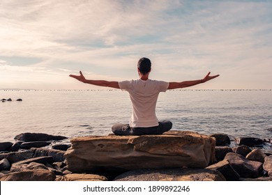 Attractive young man practicing yoga meditation and breathwork outdoors by the sea - Powered by Shutterstock