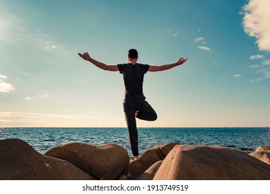 Attractive young man practicing yoga meditation and breathwork outdoors by the sea - Powered by Shutterstock