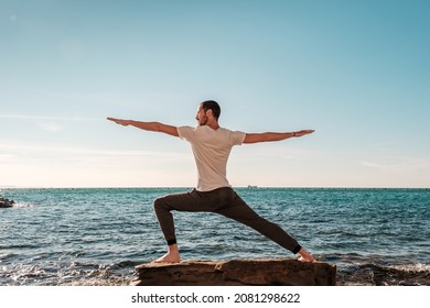 Attractive young man practicing yoga meditation and breathwork outdoors by the sea - Powered by Shutterstock