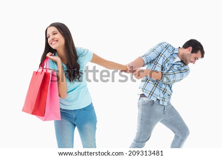 Attractive young man pulling his shopaholic girlfriend on white background
