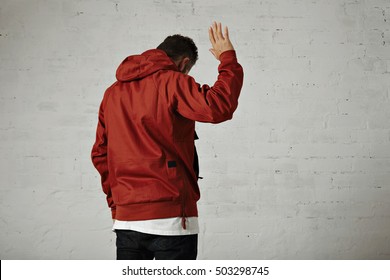 An Attractive Young Man In Red Jacket Waves Goodbye Shot From The Back Against White Wall Background