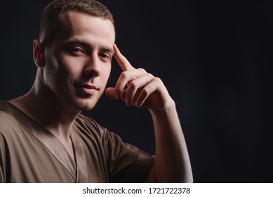 Attractive Young Man In Standing With A Pensive Look On A Dark Background. Studio Photography