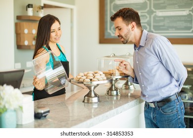 Attractive Young Man Trying To Decide What To Buy While Employee Shows Him Their Products In A Cake Shop